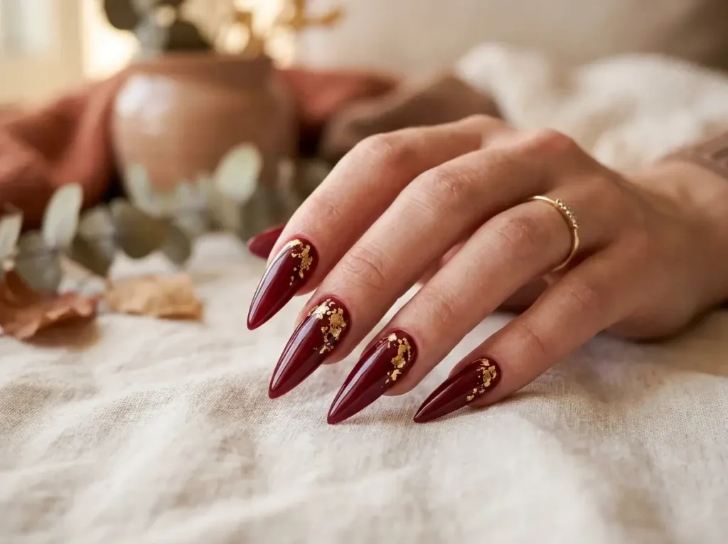 15 Trendy Fall Nail Designs You Need to Try in 2026 (Classy & Cozy Inspo) 9 Long stiletto acrylic nails painted in deep crimson red with flecks of gold leaf foil