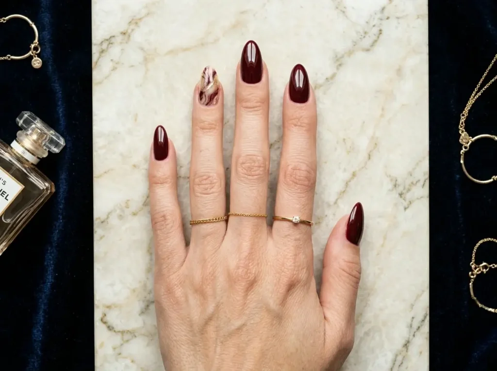 Burgundy Nail Designs: 18 Classy Ideas for Every Nail Shape (2026) 9 burgundy and gold marble nail design with glossy finish